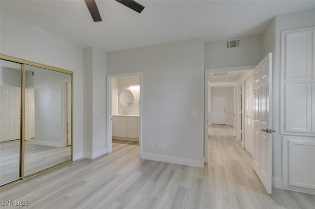 unfurnished bedroom featuring a closet, visible vents, light wood-style flooring, and baseboards