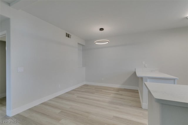 interior space featuring visible vents, light wood-style flooring, and baseboards