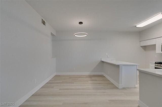 unfurnished dining area with light wood-type flooring, visible vents, and baseboards