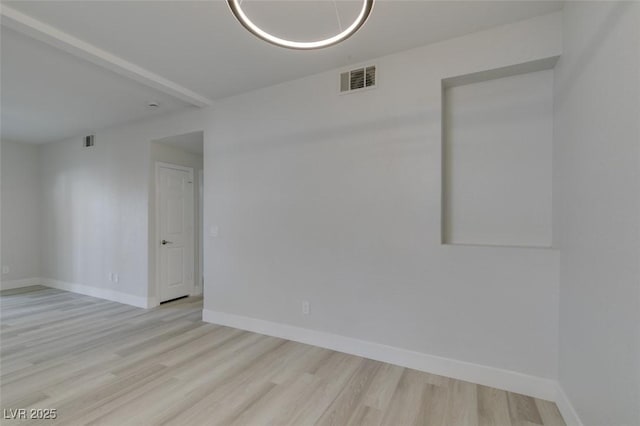 spare room featuring visible vents, baseboards, and wood finished floors