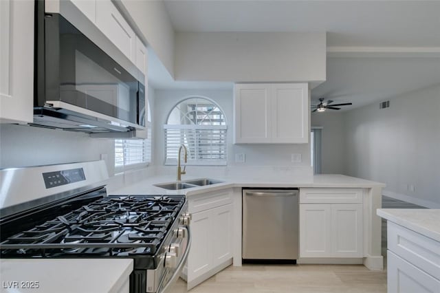 kitchen featuring visible vents, appliances with stainless steel finishes, light countertops, white cabinetry, and a sink