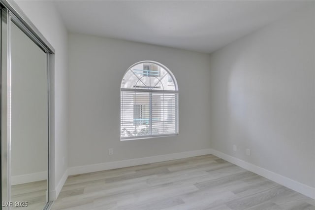 unfurnished room with light wood-style flooring and baseboards