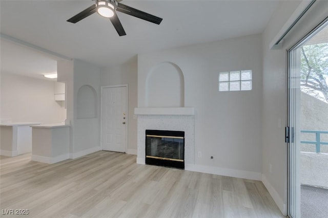 unfurnished living room featuring light wood finished floors, baseboards, a ceiling fan, and a tile fireplace