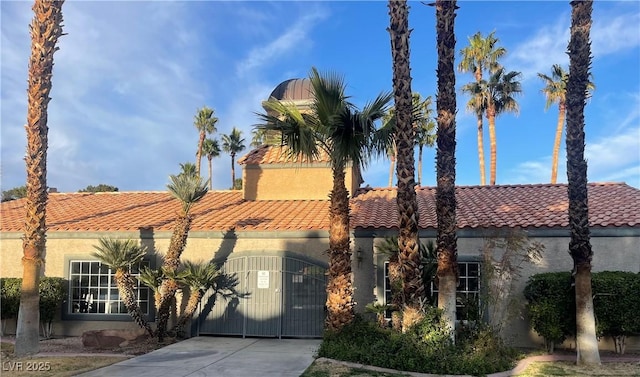 mediterranean / spanish house featuring a gate, concrete driveway, a tiled roof, and stucco siding