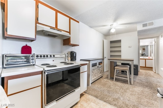 kitchen featuring a toaster, under cabinet range hood, electric stove, visible vents, and a textured ceiling
