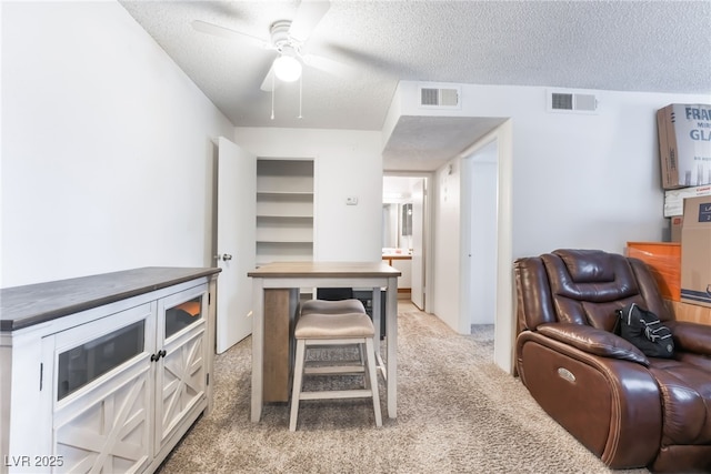 interior space with wooden counters, visible vents, light colored carpet, and ceiling fan