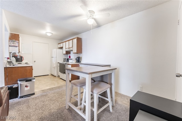 kitchen with light countertops, light carpet, ceiling fan, and white appliances
