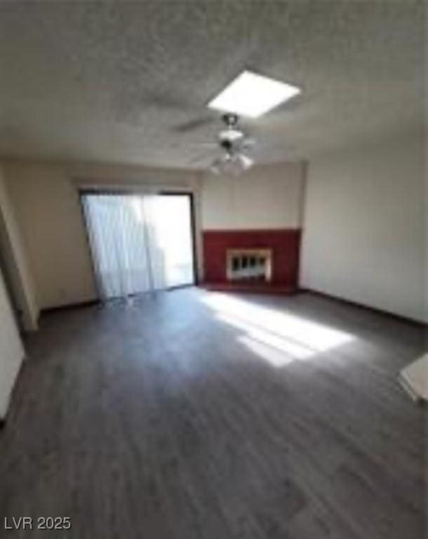 unfurnished living room featuring a ceiling fan, a skylight, and a wall mounted AC