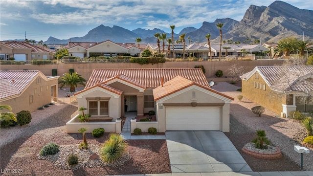 view of front of property featuring concrete driveway, a fenced front yard, a tiled roof, a mountain view, and stucco siding