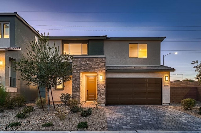 view of front of home featuring a garage, stone siding, fence, decorative driveway, and stucco siding