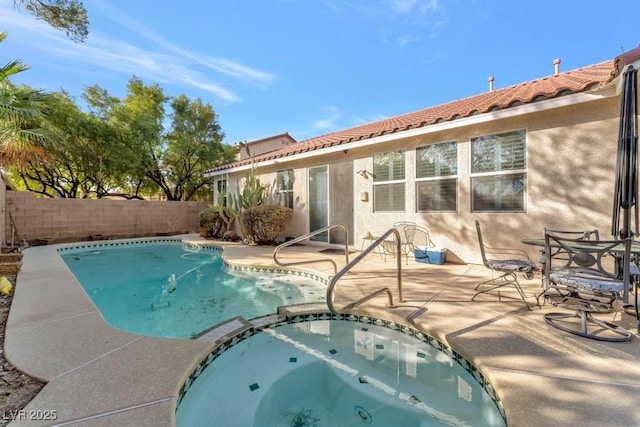 view of pool with a patio, fence, and a pool with connected hot tub