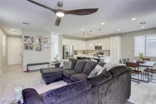 living room with stairs, recessed lighting, visible vents, and light wood-type flooring