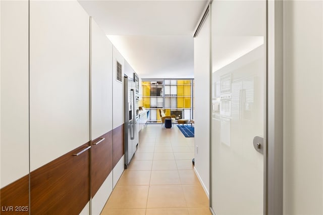 hallway featuring expansive windows and light tile patterned floors