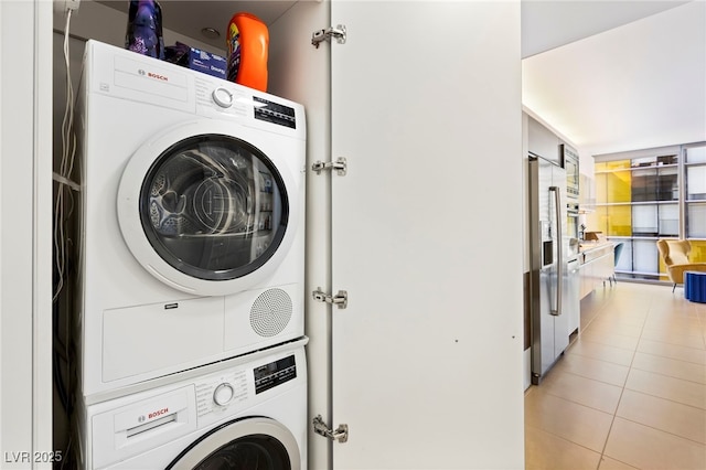 laundry area with light tile patterned floors, laundry area, and stacked washer / drying machine