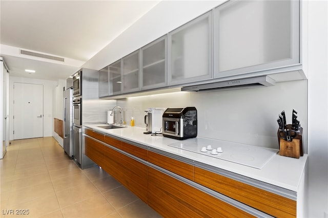 kitchen with gray cabinets, visible vents, a sink, and under cabinet range hood