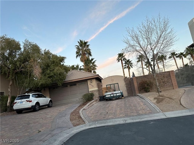 view of front of property with decorative driveway, a gate, and stucco siding