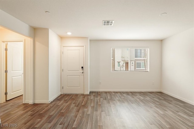 empty room with baseboards, visible vents, and wood finished floors