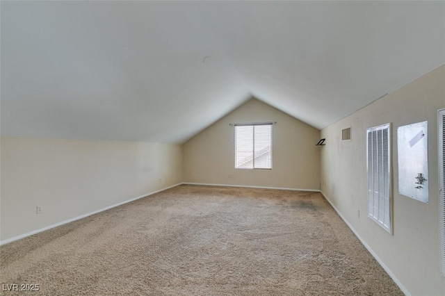 additional living space featuring carpet floors, baseboards, visible vents, and vaulted ceiling