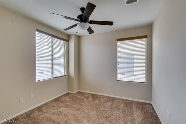 spare room with carpet floors, baseboards, visible vents, and ceiling fan