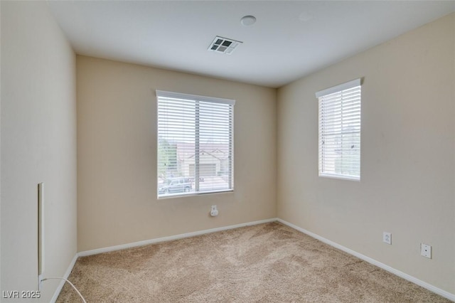 spare room with carpet, visible vents, and baseboards