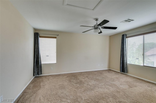 carpeted spare room featuring baseboards, visible vents, and attic access