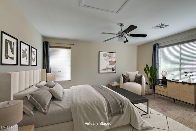 bedroom with ceiling fan, multiple windows, visible vents, and light colored carpet