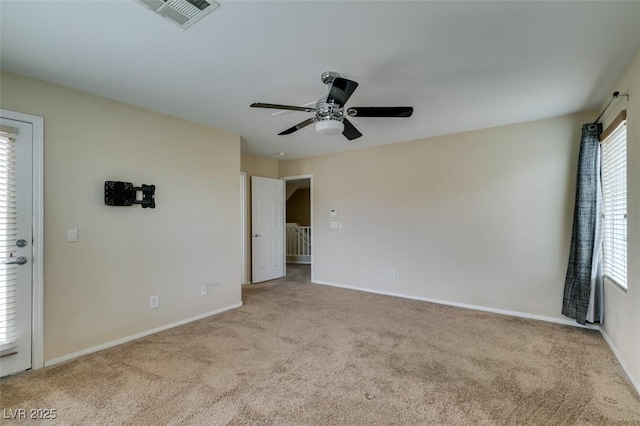 carpeted empty room featuring baseboards, visible vents, and a ceiling fan