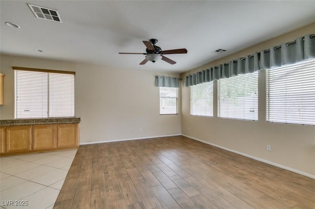 empty room featuring light wood-style floors, visible vents, and baseboards