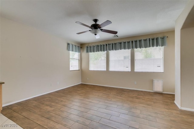 empty room with a ceiling fan, baseboards, visible vents, and wood finished floors