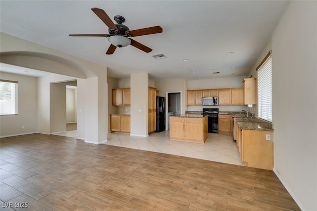 kitchen with visible vents, stove, open floor plan, stainless steel microwave, and freestanding refrigerator