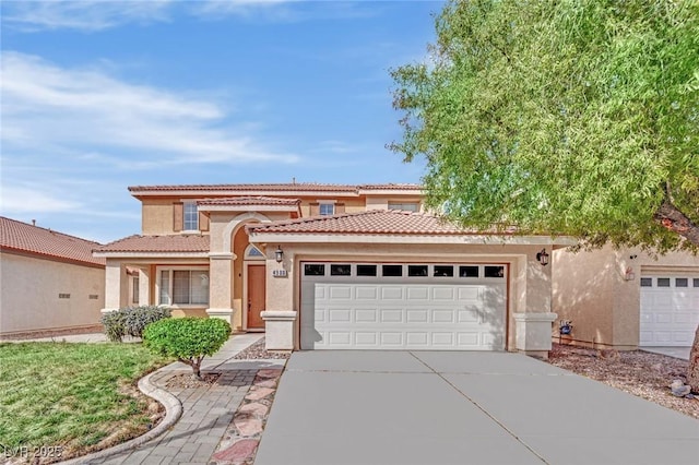 mediterranean / spanish-style house with a garage, concrete driveway, a tiled roof, and stucco siding