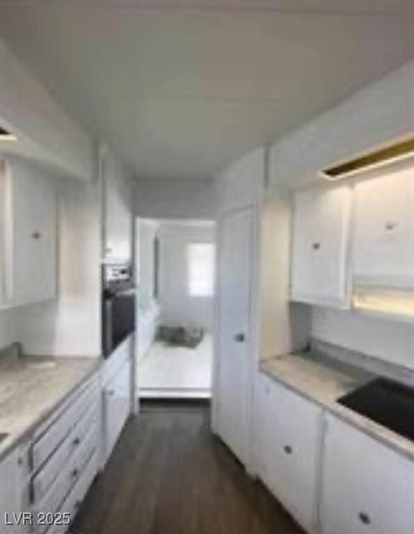 kitchen with dark wood-type flooring, light countertops, white cabinetry, and stainless steel oven