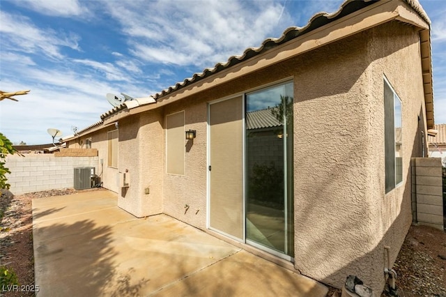 exterior space with a patio area, fence, central AC unit, and stucco siding