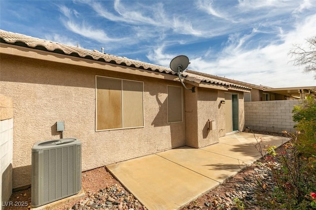 view of property exterior with a patio, cooling unit, fence, a tiled roof, and stucco siding