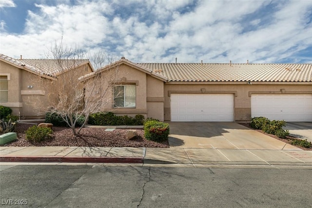 view of front of property with concrete driveway, an attached garage, a tile roof, and stucco siding