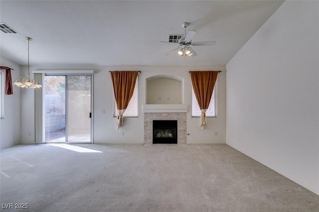 unfurnished living room featuring carpet floors, visible vents, a tiled fireplace, and ceiling fan with notable chandelier