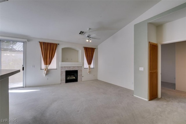 unfurnished living room with carpet, a tiled fireplace, visible vents, and a ceiling fan