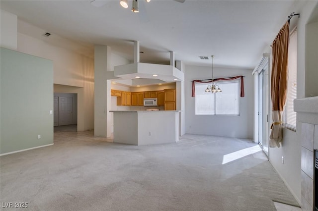 unfurnished living room featuring light colored carpet, vaulted ceiling, visible vents, and ceiling fan with notable chandelier