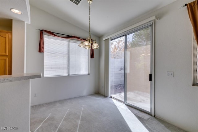 unfurnished dining area with vaulted ceiling, light carpet, a chandelier, and visible vents