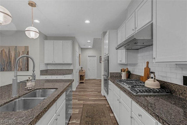 kitchen featuring decorative light fixtures, stainless steel appliances, white cabinetry, a sink, and under cabinet range hood