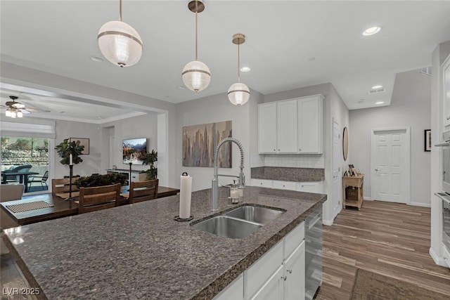 kitchen featuring decorative light fixtures, dark wood finished floors, recessed lighting, white cabinetry, and a sink