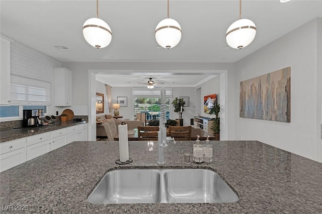 kitchen featuring white cabinets, visible vents, hanging light fixtures, and dark stone countertops