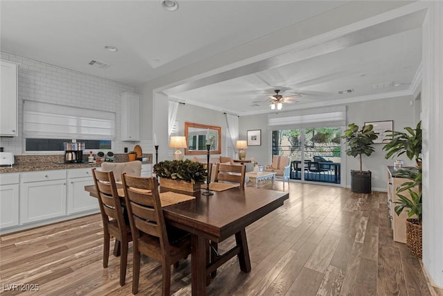 dining space with ornamental molding, light wood-type flooring, visible vents, and a ceiling fan