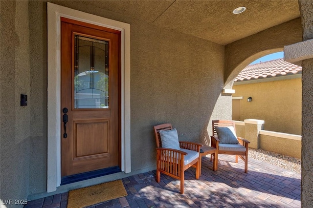 view of exterior entry featuring a patio, a tiled roof, and stucco siding