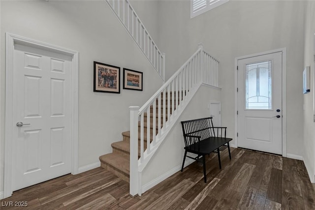 foyer featuring a high ceiling, stairs, baseboards, and dark wood-style flooring