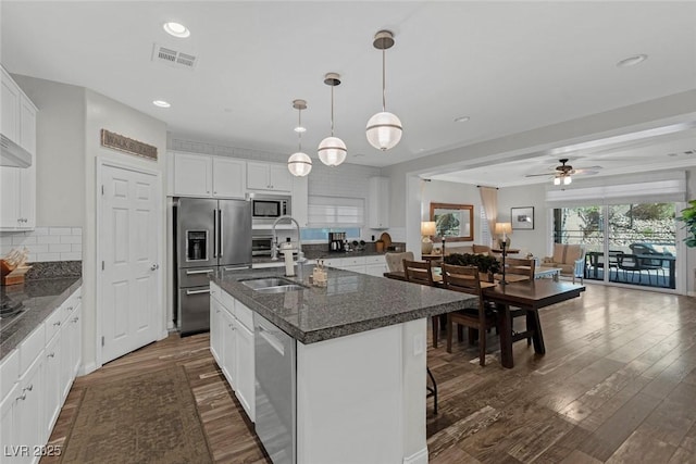 kitchen with visible vents, decorative backsplash, appliances with stainless steel finishes, dark wood-type flooring, and a sink