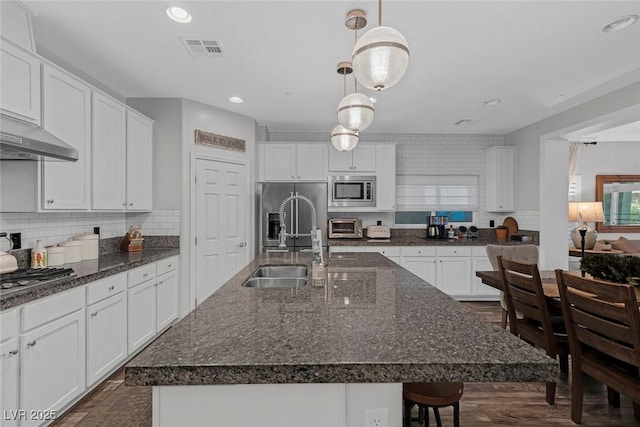 kitchen with visible vents, appliances with stainless steel finishes, a breakfast bar, white cabinetry, and backsplash