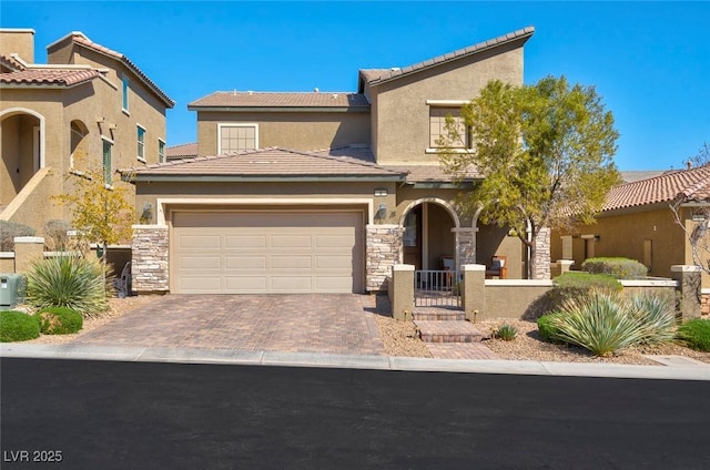 mediterranean / spanish-style house with an attached garage, stone siding, decorative driveway, and stucco siding