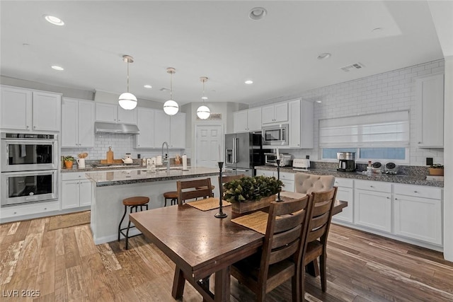 dining area with light wood-style floors, recessed lighting, and visible vents