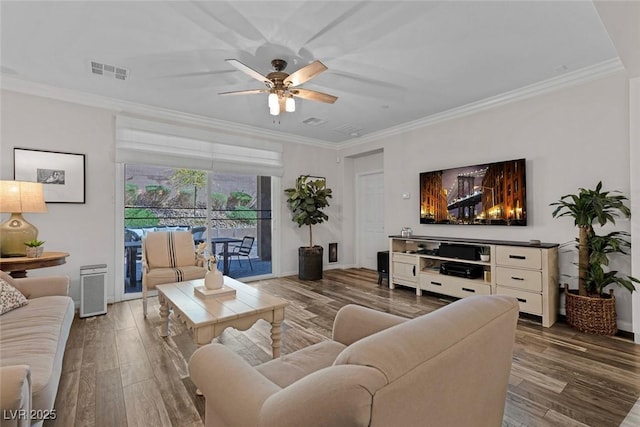 living room with a ceiling fan, crown molding, visible vents, and wood finished floors